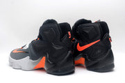 Rear view of the black Nike high-top shoes with orange side accents and contrasting white midsoles.