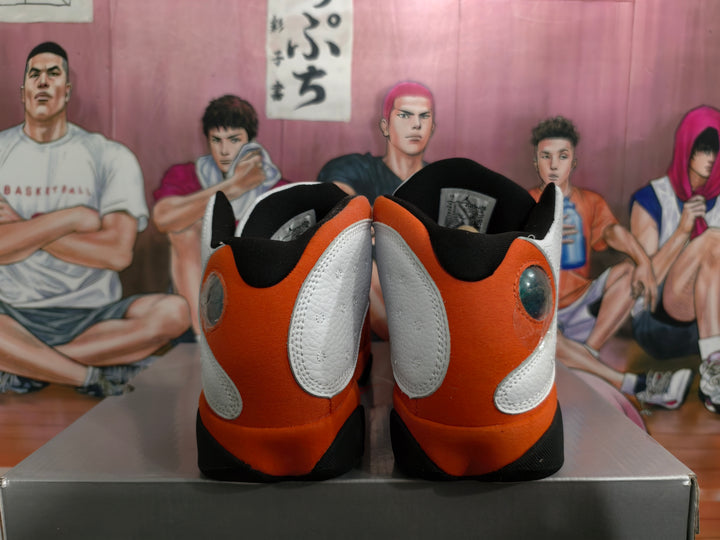Rear view of white, orange, and black Jordan 13-style high-top sneakers