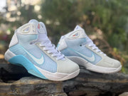 Angled front view showing white laces, padded high-top collars, light blue uppers, and white toe panels.