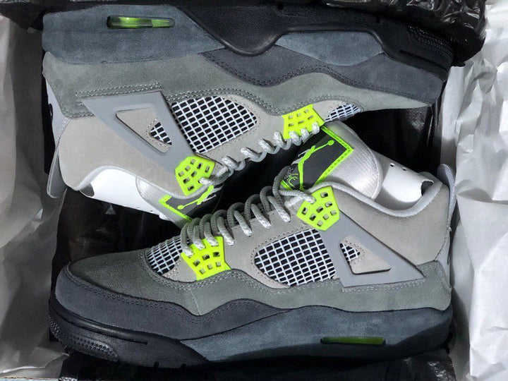 Pair of grey and black Air Jordan 4-style sneakers with bright green accents and mesh side panels.