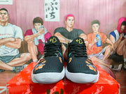 Front view of black Nike sneakers with black laces, gold tongue details, multicolor side graphics, and white outsoles.