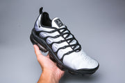 Nike TN-12 sneaker in gray, white, and black, shown at an angle.