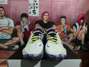 Front view of the paired basketball sneakers showing purple tongues, yellow laces, white toe boxes, and translucent outsoles.