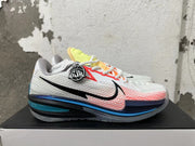 Side view of a white mesh-patterned Nike basketball shoe with black and blue details and coral accents.