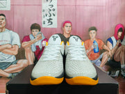Front view of the textured white basketball shoes with Kobe logos on the tongues and yellow-orange outsoles.