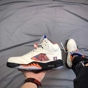 Close side view of a white high-top sneaker with white laces, patterned side panel, number 23 detail, and visible midsole window.