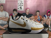 Side profile of a white Nike basketball sneaker with gold swoosh detailing, perforated panels, and visible ZoomX text.