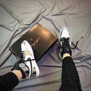 Pair of white and silver high-top sneakers displayed beside a black shoebox.