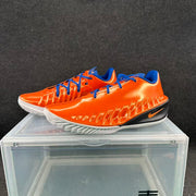 Pair of orange Nike GT low-top basketball shoes with blue laces