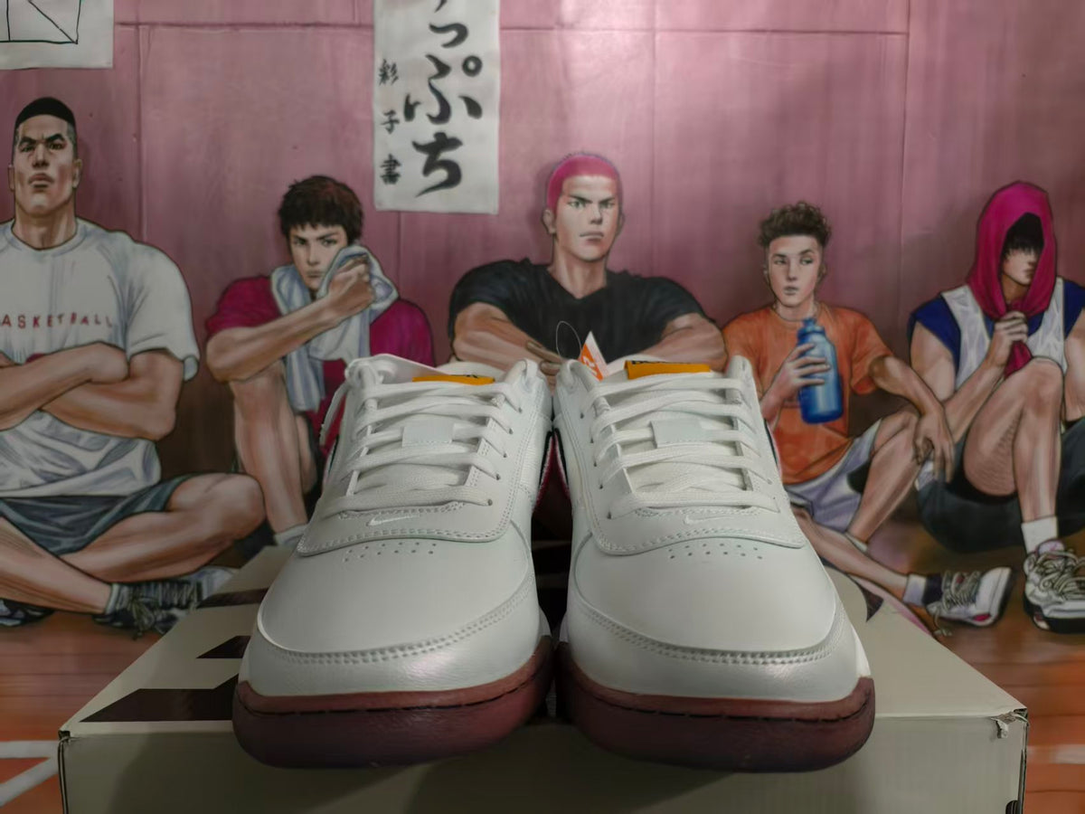 Front view of white low-top basketball sneakers with blue and gum-toned outsole accents.