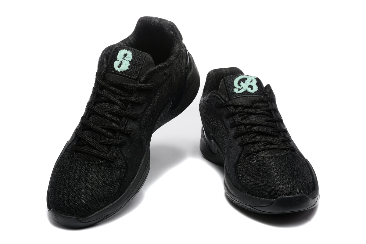 Pair of black low-top Nike basketball sneakers shown from the front and three-quarter angle with mint-green tongue graphics.