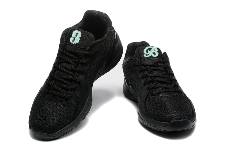 Pair of black low-top Nike basketball sneakers shown from the front and three-quarter angle with mint-green tongue graphics.