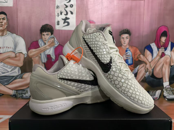 Pair of off-white Nike KD basketball sneakers displayed on a black shoe box, showing the black Swoosh, raised star detailing, and textured forefoot.