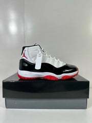 Side view highlighting the white upper, glossy black lower panels, white midsole, and red outsole.