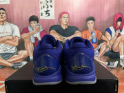 Rear view of blue Nike basketball sneakers showing gold signature-style heel graphics and translucent outsoles on a black box.