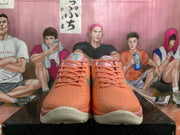 Front view of coral-orange Nike Kobe basketball shoes with pink tongue details and teal accents.