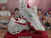 Angled view of white Nike sneakers with red trim, contrasting green and red Swoosh details, and a sculpted outsole.