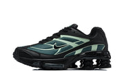 Side view of a black Nike Shox Ride 2 sneaker with teal and pale green panels and visible heel columns.