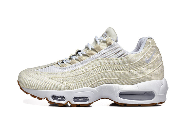 Side view of a cream Nike low-top sneaker with layered wavy panels, mesh details, white sole, visible air units, and gum-colored outsole.