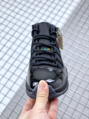 Front view of the black sneaker with black laces, glossy toe and small blue-and-yellow tongue branding.
