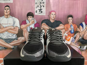 Front view of the pair of black and light-gray Nike sneakers, showing the laces, textured toe panels, and padded tongues.
