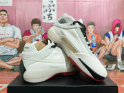 Angled side view of white Jordan high-top basketball shoes with black laces and red outsole accents.