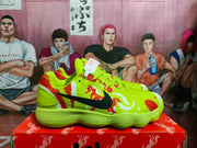 Side view of a bright yellow Nike sneaker with red and black patterned accents, displayed on a red shoebox.