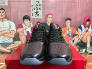 Front view of black basketball sneakers with purple accents, black laces, perforated toe panels and gold tongue details.