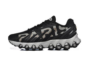 Side view of black Nike Air Max DN 8 Paris sneakers with gray and beige lettering and a white sculpted sole.