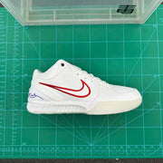 Side profile of the white and red sneaker photographed on a green cutting mat.