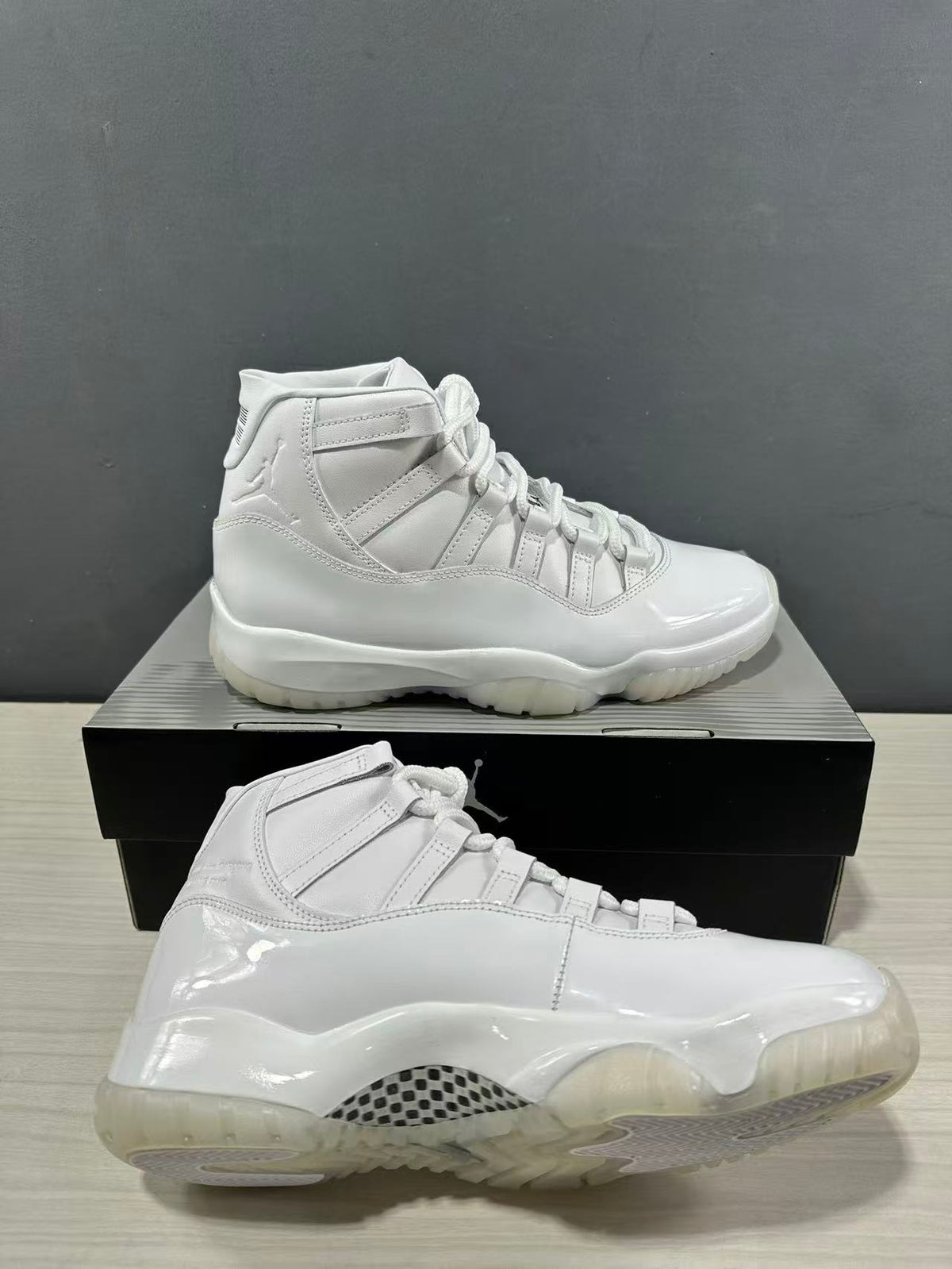White high-top sneakers shown from the side on a black shoebox, with glossy panels and a translucent outsole.