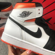 Close-up of the black Swoosh, ankle wing logo, white panels, and orange outsole.