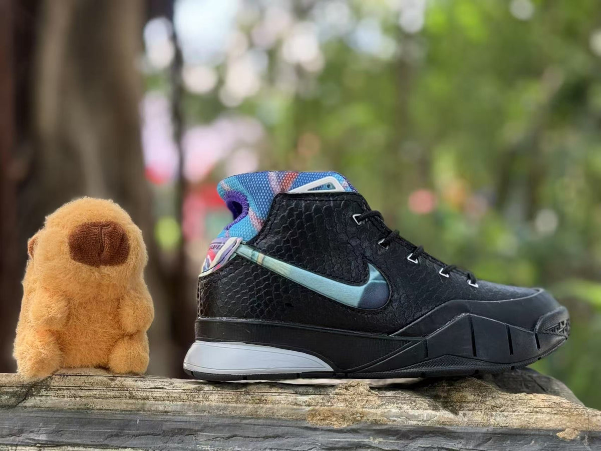 Side view of a black kids’ Kobe 1 basketball shoe with a blue accent and colorful collar.