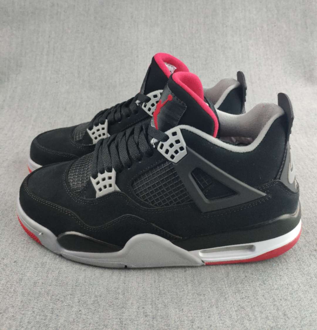 Pair of black Jordan 4-style sneakers with white eyelets, red accents, and layered soles.