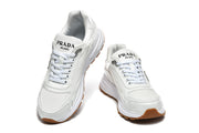 Front view of white Prada low-top sneakers with lace-up fronts and sculpted soles.