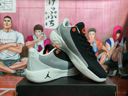 Angled view of the pair showing the black and gray uppers, orange accents, Jordan branding, and white soles.