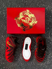 Pair of brown and red sneakers arranged around a red horse-themed shoebox, with one sole exposed.