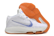 Side view of a white shoe with blue details and orange outsole.
