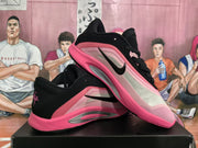 Angled side view showing the black side mark, pale upper, pink panels and layered sole.