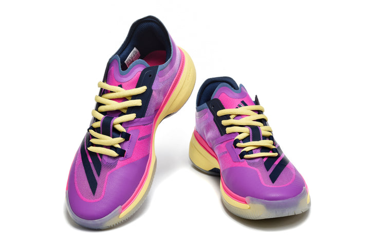 Pair of purple and pink adidas low-cut shoes with dark stripes, yellow laces and yellow-toned soles, shown from the front.