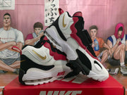 Angled view of the Nike sneakers showing the white, red, and black color blocking and visible heel air unit.