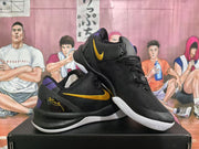 Angled view of the black and yellow Nike sneaker pair with purple details and white outsoles.