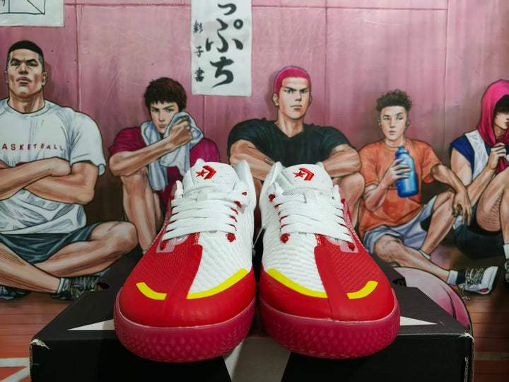 Pair of white and red Converse sneakers shown from the front with yellow toe accents and red laces.