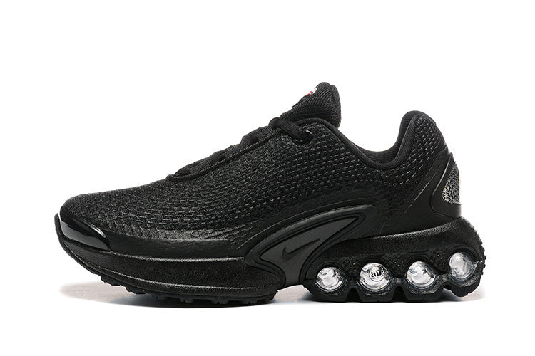 Side view of a black Nike low-top sneaker with a textured upper and four visible circular heel cushioning units.