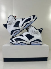 Angled side view of the white and navy high-top sneakers arranged on a shoebox.
