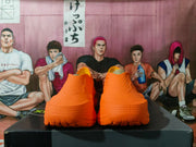Rear view of the orange sneakers showing the textured heel sections and segmented outsole edges.