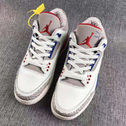 Front view of the pair showing the red Jumpman tongue logos, white uppers, blue accents, and patterned grey toe panels.
