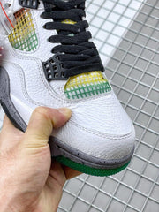 Close-up of the white Jordan sneaker toe box, black laces, black lace hardware, and green-and-yellow mesh.