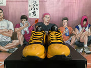 Front view showing yellow perforated toe panels, black uppers, yellow laces, and basketball-style tongue logos.
