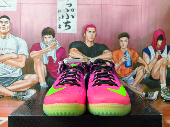 Front view of bright pink Nike basketball shoes with neon green accents and black laces.